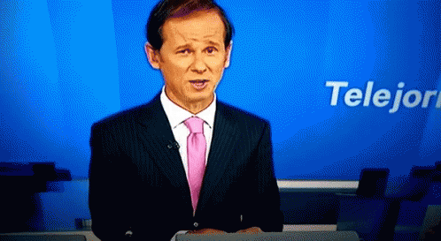 A Man In A Suit And Pink Tie Is Standing In Front Of A Blue Background That Says Telejon GIF