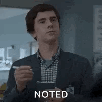 A Man In A Suit And Plaid Shirt Is Holding A Pen And A Clipboard . GIF