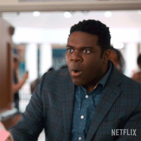 A Man In A Suit And Polka Dot Shirt Looks Surprised With His Mouth Open .. GIF