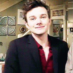 A Man In A Suit And Red Shirt Is Standing In A Living Room . GIF
