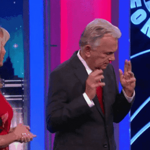 A Man In A Suit And Red Tie Is Dancing In Front Of A Woman In A Red Dress GIF