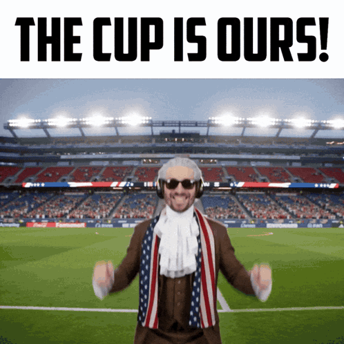 a man in a suit and scarf stands in front of a soccer stadium with the words the cup is ours