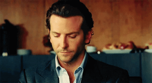 A Man In A Suit And Striped Shirt Is Looking Down With His Eyes Closed GIF