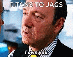 A Man In A Suit And Striped Shirt Is Talking To Another Man With The Caption Titans To Jags I Own You GIF