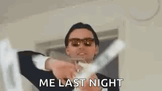 A Man In A Suit And Sunglasses Is Holding A Glass Of Champagne In His Hands . GIF