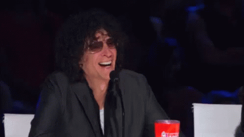 A Man In A Suit And Sunglasses Is Laughing While Sitting At A Table . GIF