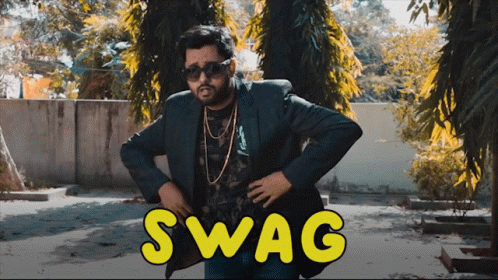 A Man In A Suit And Sunglasses Stands In Front Of A Sign That Says Swag On It GIF