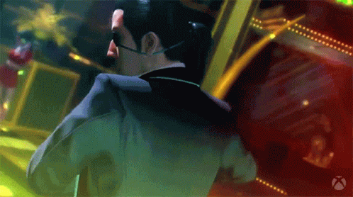 A Man In A Suit And Sunglasses Stands In Front Of A Xbox Logo GIF