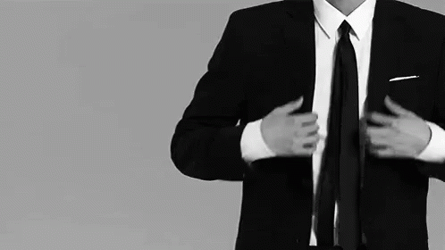 A Man In A Suit And Tie Adjusts His Tie GIF