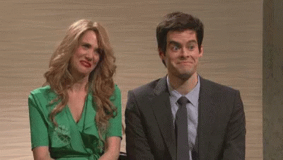 A Man In A Suit And Tie And A Woman In A Green Dress Are Sitting Next To Each Other Making Funny Faces . GIF