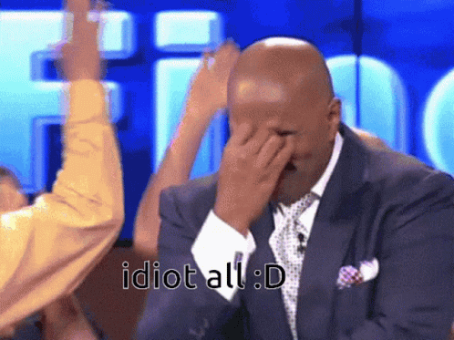 A Man In A Suit And Tie Covering His Face With His Hand With The Words Idiot All : D Written Below Him GIF
