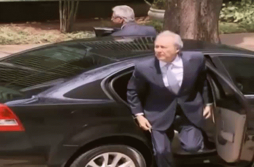 A Man In A Suit And Tie Gets Out Of A Car GIF