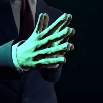 A Man In A Suit And Tie Has A Green Hand GIF