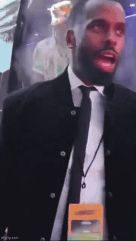 A Man In A Suit And Tie Has A Lanyard Around His Neck That Says ' Security ' GIF