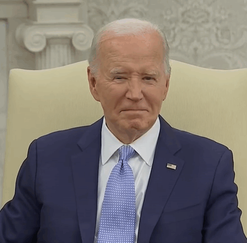 A Man In A Suit And Tie Has A Pin On His Jacket That Says ' United States Of America ' On It GIF