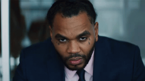A Man In A Suit And Tie Has A Tattoo On His Face GIF