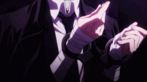A Man In A Suit And Tie Has His Hands Wrapped In Bandages And Handcuffs . GIF