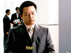 A Man In A Suit And Tie Has The Word Heart Written On His Jacket GIF