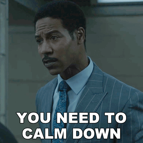 a man in a suit and tie has the words you need to calm down below him