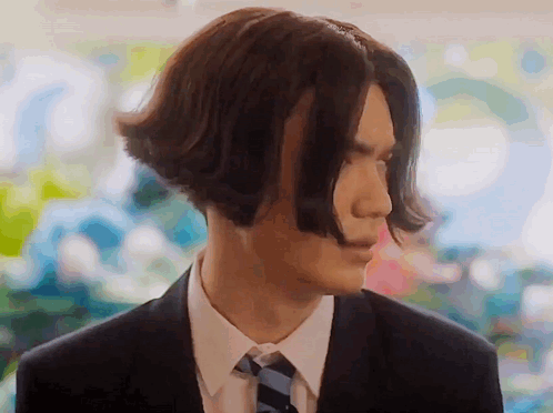A Man In A Suit And Tie Has Very Long Hair . GIF