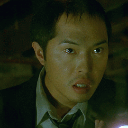A Man In A Suit And Tie Holding A Flashlight GIF