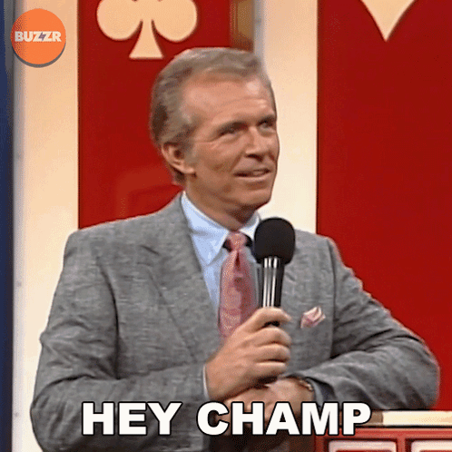 A Man In A Suit And Tie Holding A Microphone And Saying Hey Champ GIF