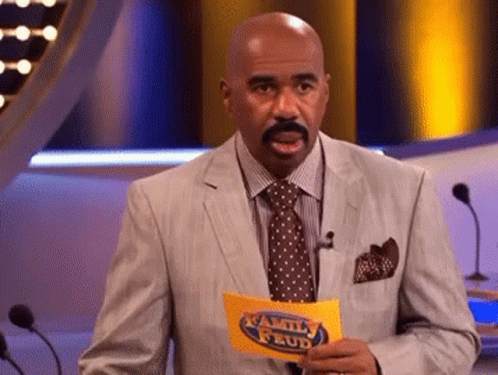 A Man In A Suit And Tie Holds A Family Feud Sign GIF