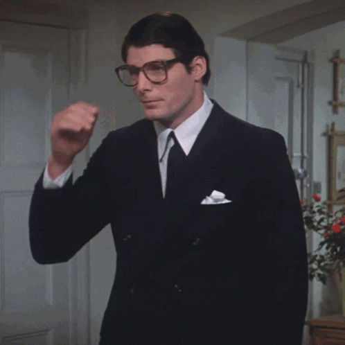 A Man In A Suit And Tie Holds A Pair Of Sunglasses GIF