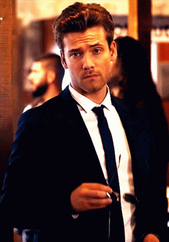 A Man In A Suit And Tie Holds A Pair Of Sunglasses In His Hand GIF