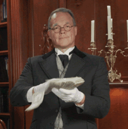 A Man In A Suit And Tie Holds A Piece Of Paper In His Hands GIF