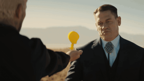 a man in a suit and tie holds a yellow object in his hand