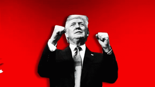 A Man In A Suit And Tie Holds His Fist In The Air GIF