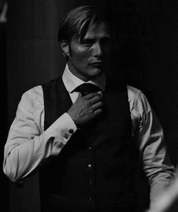 A Man In A Suit And Tie Is Adjusting His Jacket . GIF