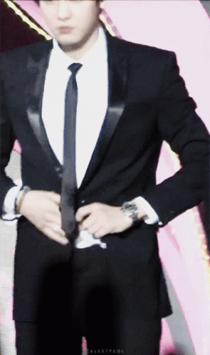 A Man In A Suit And Tie Is Adjusting His Suit Jacket GIF