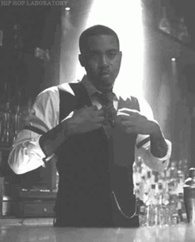 A Man In A Suit And Tie Is Adjusting His Tie In A Black And White Photo . GIF