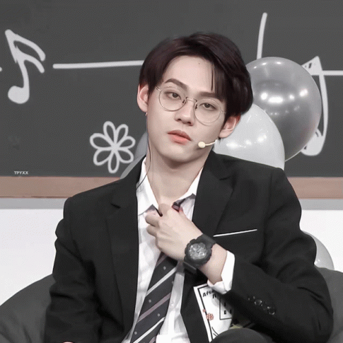a man in a suit and tie is adjusting his tie while wearing a watch