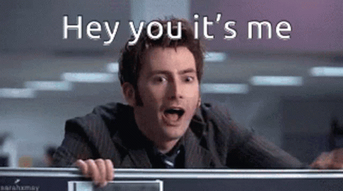 a man in a suit and tie is behind a desk and says hey you it 's me