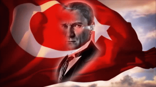 A Man In A Suit And Tie Is Behind A Turkey Flag GIF