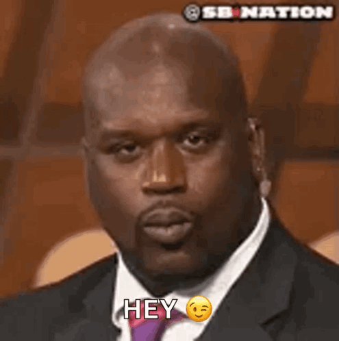 A Man In A Suit And Tie Is Blowing A Kiss And Says Hey GIF