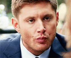 A Man In A Suit And Tie Is Blowing A Kiss At The Camera . GIF