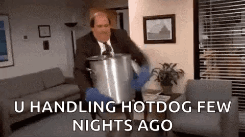A Man In A Suit And Tie Is Carrying A Large Pot In A Living Room . GIF