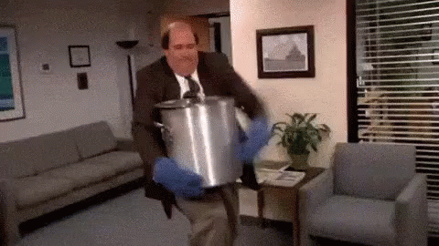 A Man In A Suit And Tie Is Carrying A Large Pot . GIF