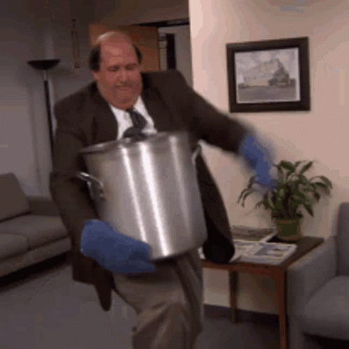 A Man In A Suit And Tie Is Carrying A Pot GIF