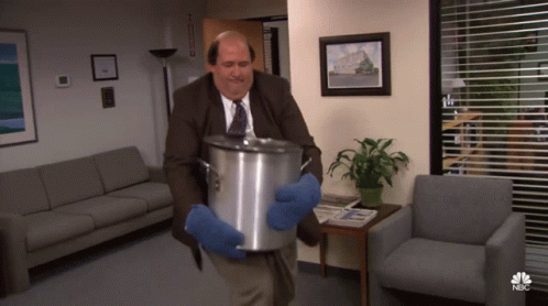 A Man In A Suit And Tie Is Carrying A Pot With A Nbc Logo On The Bottom GIF