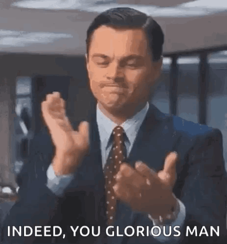 A Man In A Suit And Tie Is Clapping His Hands And Saying `` Indeed You Glorious Man '' . GIF