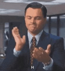 a man in a suit and tie is clapping his hands and says h .