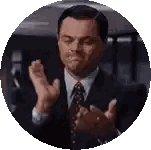 a man in a suit and tie is clapping his hands in a circle with his eyes closed .