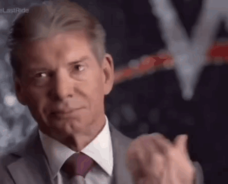 A Man In A Suit And Tie Is Clapping His Hands In Front Of A Blurred Background . GIF