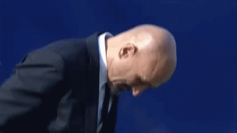 A Man In A Suit And Tie Is Clapping His Hands . GIF