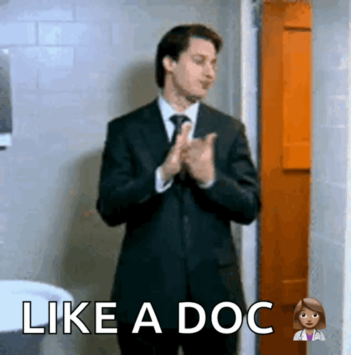 A Man In A Suit And Tie Is Clapping His Hands With The Words Like A Doc Above Him GIF